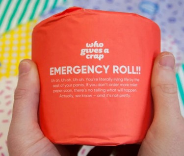 Who gives a crap brand voice example hands holding a red emergency roll of toilet roll.