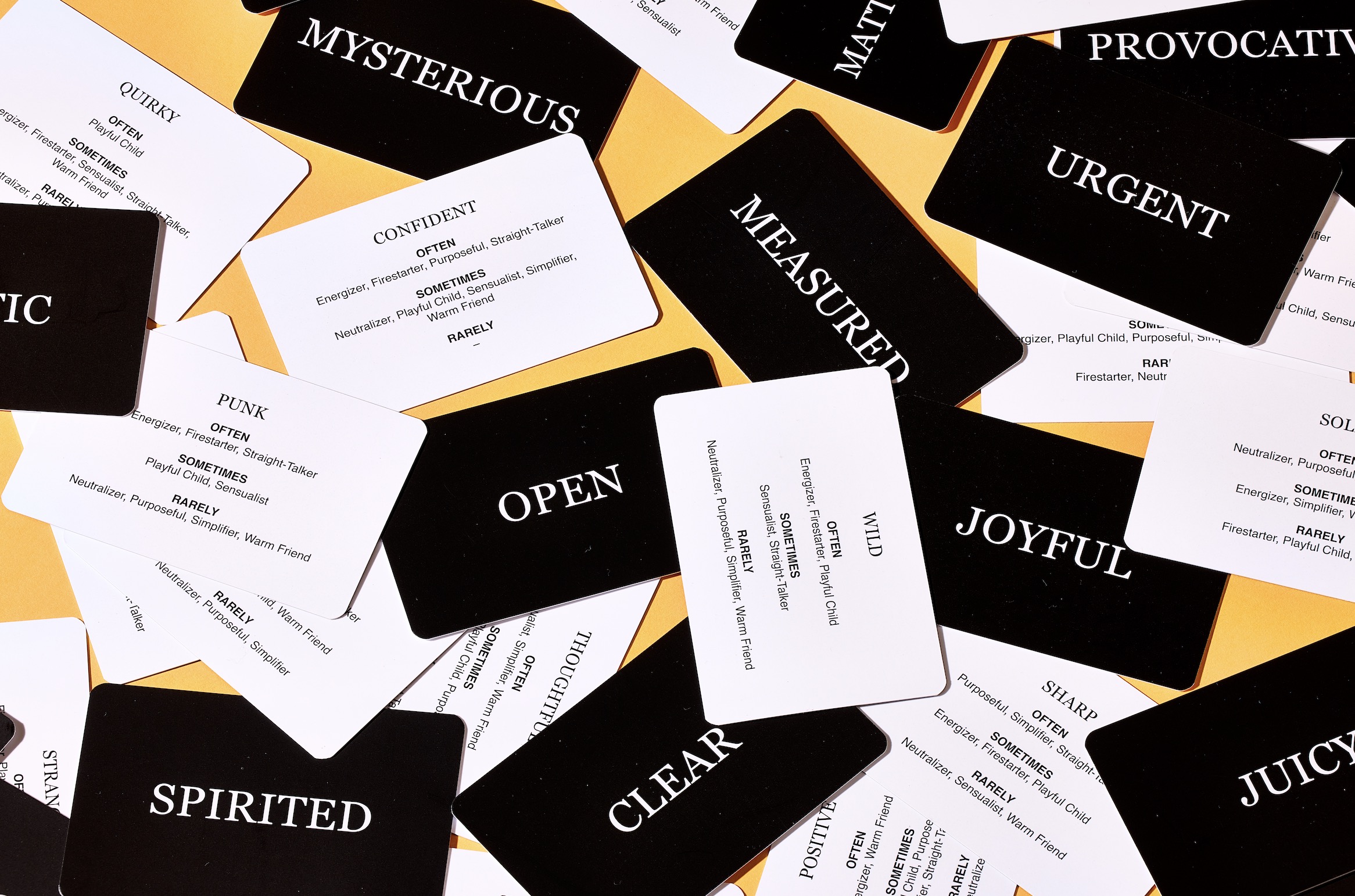 a pack of 'tone of voice tarot cards' with one word on the black side, and a longer description on the back .