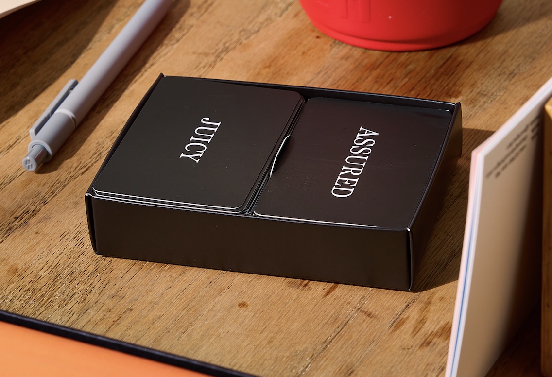 a pack of 'tone of voice tarot cards' with one word on the black side, and a longer description on the back .