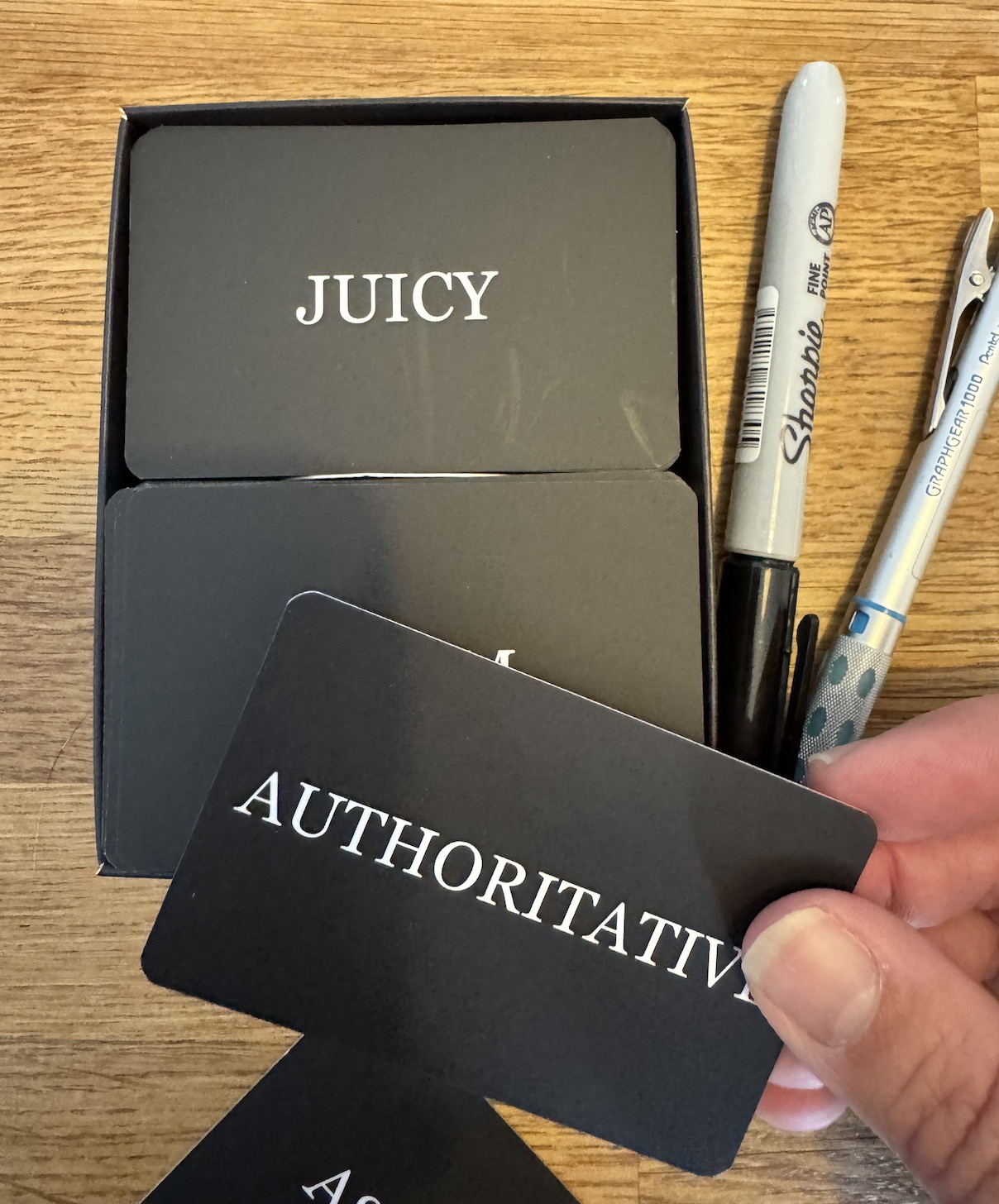 a pack of 'tone of voice tarot cards' with one word on the black side, and a longer description on the back .