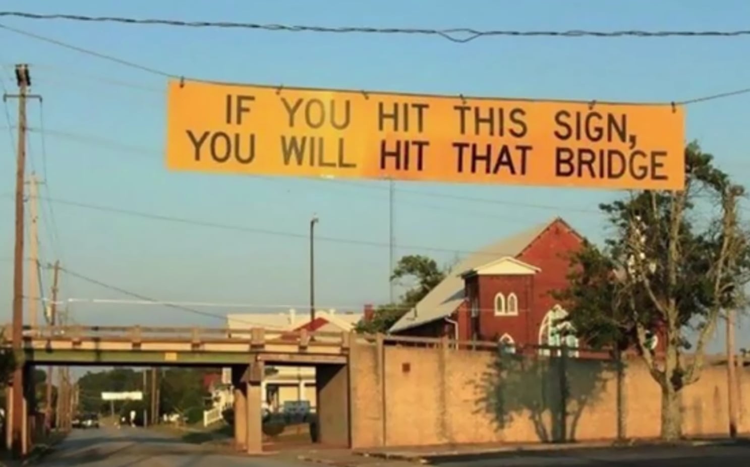 A sign in front of a bridge in Griffin, Georgia, USA that reads “If you hit this sign, you will hit that bridge.”.